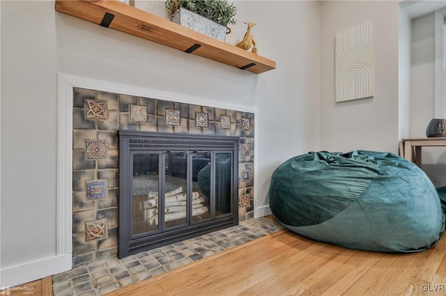 interior details featuring wood finished floors and a tile fireplace