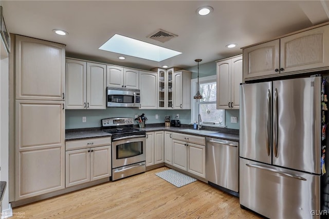 kitchen with decorative light fixtures, dark countertops, visible vents, appliances with stainless steel finishes, and a sink