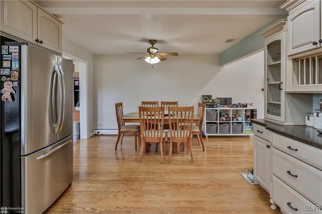 kitchen featuring dark countertops, baseboard heating, light wood-style floors, freestanding refrigerator, and ceiling fan