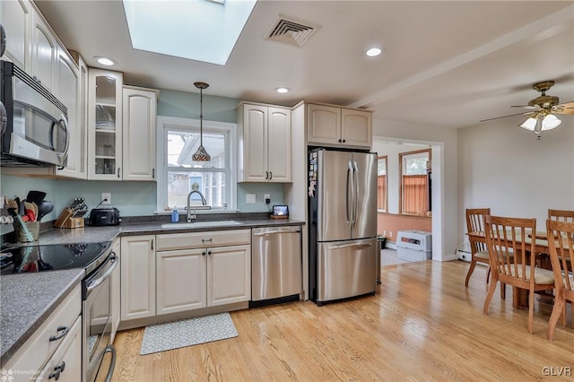 kitchen with visible vents, dark countertops, decorative light fixtures, stainless steel appliances, and a sink