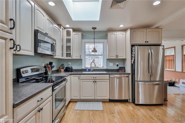 kitchen with visible vents, light wood-style flooring, appliances with stainless steel finishes, hanging light fixtures, and a sink