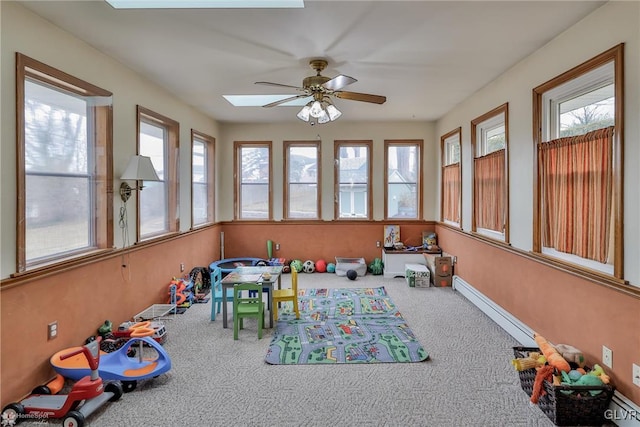 sunroom with a ceiling fan and a baseboard heating unit