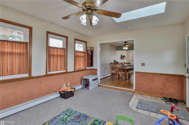 playroom with baseboard heating, a skylight, and a ceiling fan