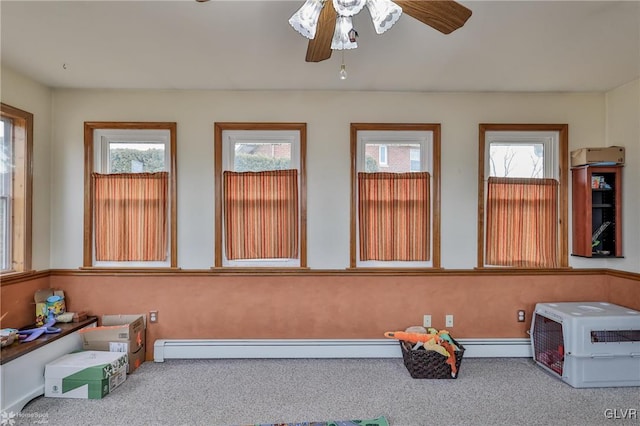 sunroom featuring a baseboard heating unit and a ceiling fan