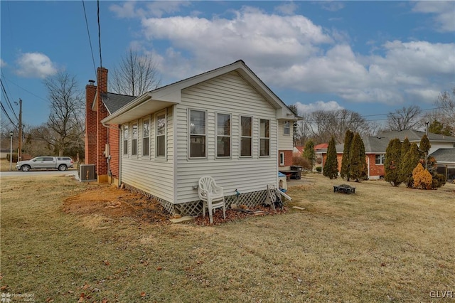 view of property exterior with central air condition unit, a chimney, and a yard