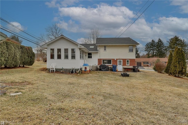 back of house featuring brick siding, an outdoor fire pit, and a yard