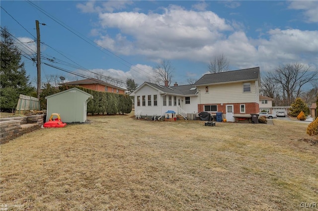 rear view of house featuring brick siding, a shed, a lawn, and an outbuilding