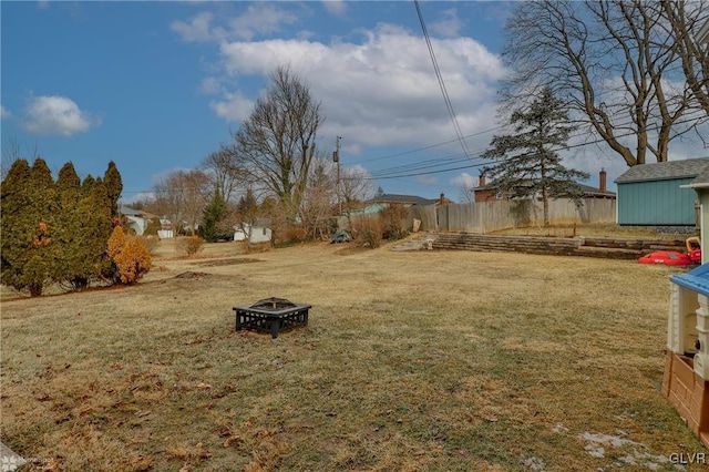 view of yard with a storage unit, fence, a fire pit, and an outdoor structure