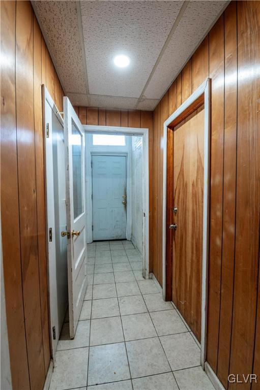 corridor featuring light tile patterned floors and wooden walls