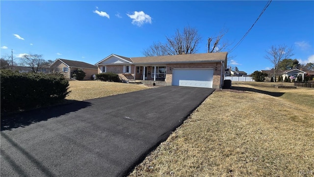 single story home featuring an attached garage, a front lawn, aphalt driveway, and brick siding