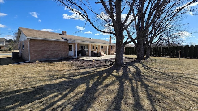 back of property featuring a patio area, a chimney, fence, and brick siding