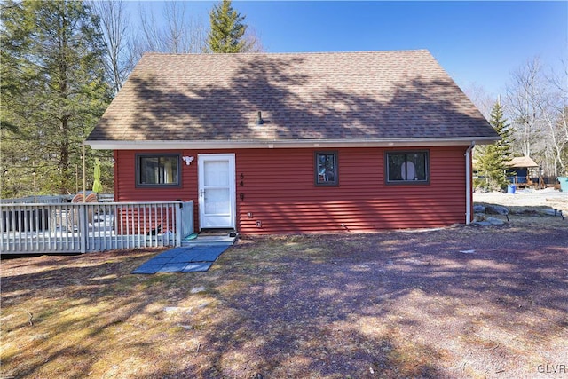 exterior space with roof with shingles and a deck