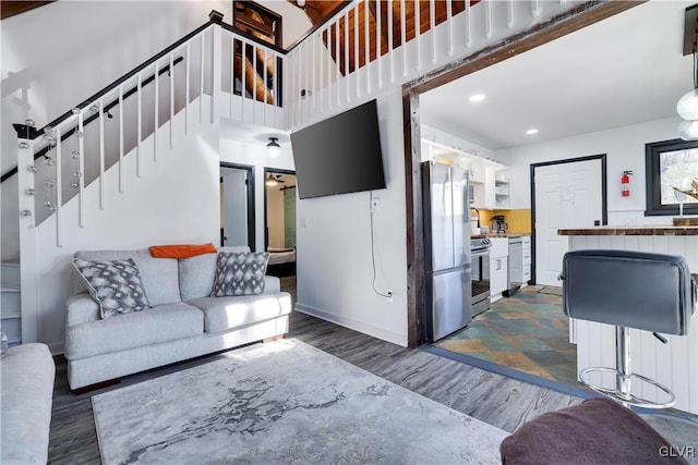 living room featuring baseboards, dark wood finished floors, stairs, recessed lighting, and a towering ceiling