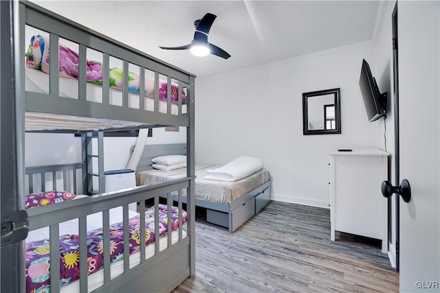 bedroom featuring ceiling fan, wood finished floors, baseboards, and ornamental molding