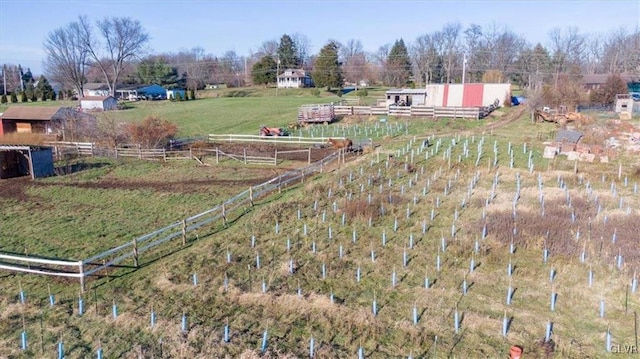 view of yard featuring a rural view, an outdoor structure, and fence