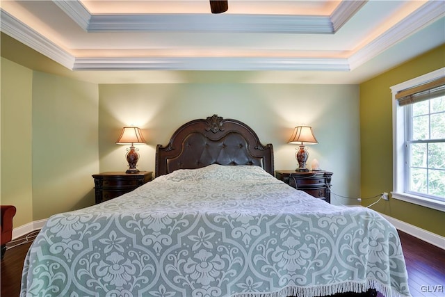 bedroom with ornamental molding, a raised ceiling, dark wood-type flooring, and baseboards