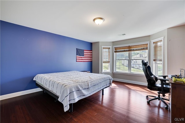 bedroom with visible vents, baseboards, and wood finished floors