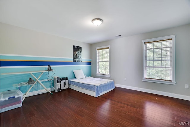 unfurnished bedroom featuring baseboards, visible vents, and wood finished floors