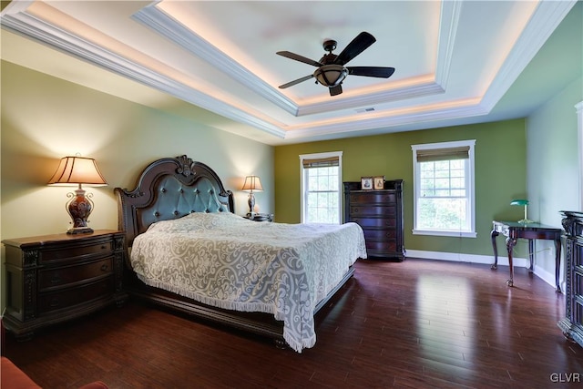 bedroom with baseboards, visible vents, a raised ceiling, ornamental molding, and dark wood-type flooring