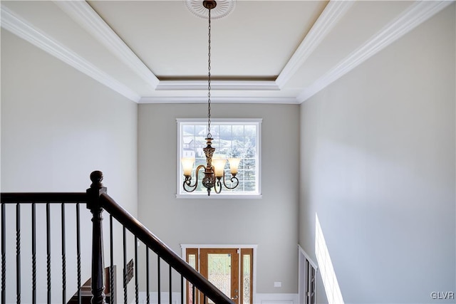 staircase with a chandelier, a tray ceiling, and crown molding