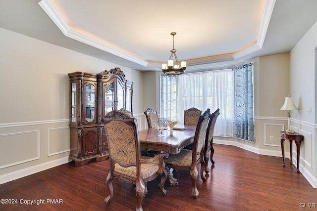 dining room featuring dark wood-style floors, an inviting chandelier, a raised ceiling, and a decorative wall