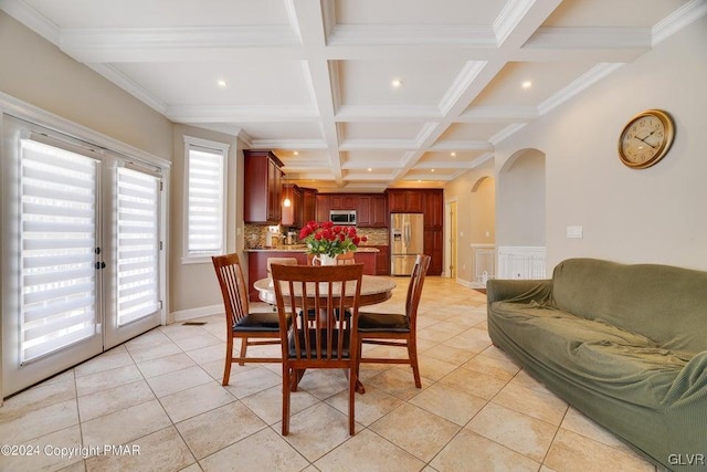 dining room with light tile patterned floors, arched walkways, coffered ceiling, and beam ceiling