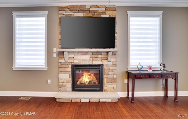 room details featuring visible vents, a stone fireplace, baseboards, and wood finished floors