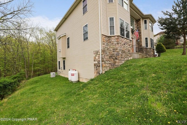 view of side of home with stone siding and a lawn