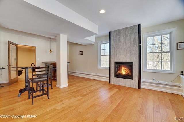 living room featuring recessed lighting, baseboards, a fireplace, and light wood finished floors