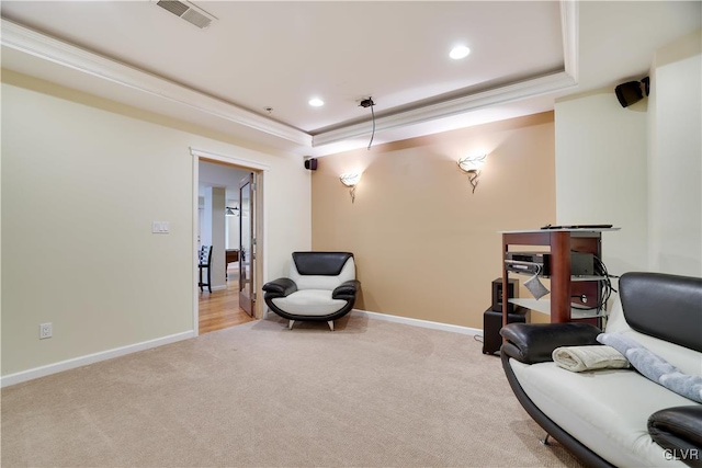 living area featuring light carpet, a tray ceiling, crown molding, and baseboards