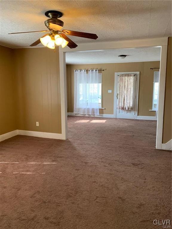 unfurnished room with a textured ceiling, carpet, and a ceiling fan