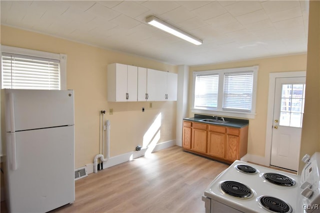 kitchen with visible vents, light wood-style floors, brown cabinetry, a sink, and white appliances