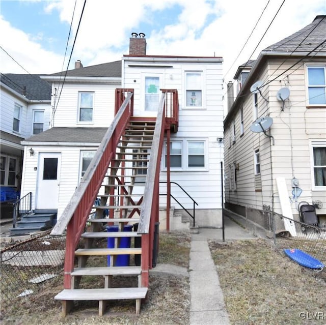 back of property featuring entry steps, fence, a chimney, and stairs