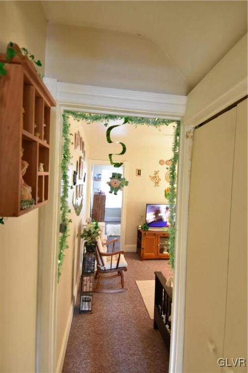 hallway with lofted ceiling, carpet flooring, and baseboards