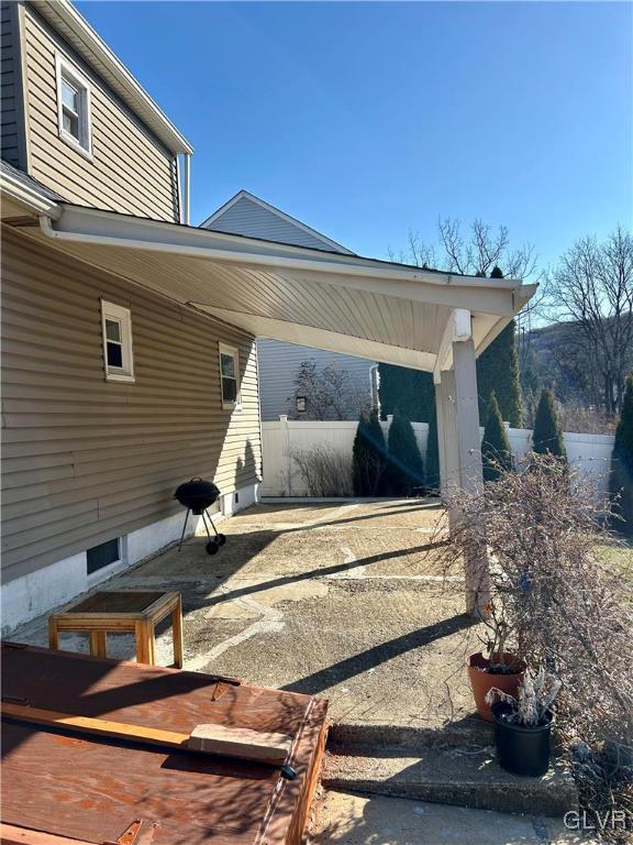 view of patio / terrace with an attached carport, fence, and driveway