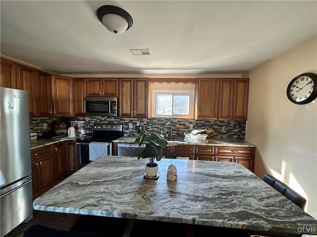 kitchen featuring stainless steel appliances, visible vents, decorative backsplash, and light stone countertops