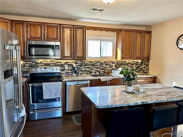 kitchen featuring a sink, visible vents, appliances with stainless steel finishes, decorative backsplash, and dark wood-style floors