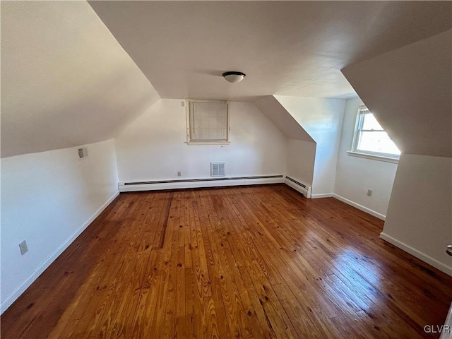 additional living space with lofted ceiling, a baseboard radiator, hardwood / wood-style flooring, and baseboards