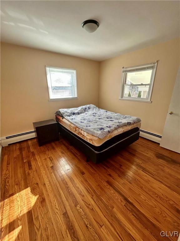 bedroom featuring baseboard heating and wood finished floors