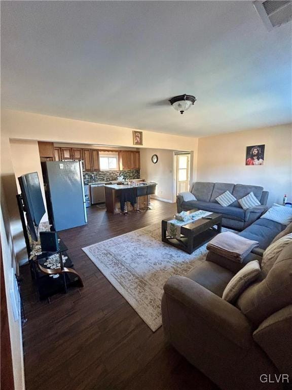 living area featuring dark wood-type flooring, visible vents, and a healthy amount of sunlight