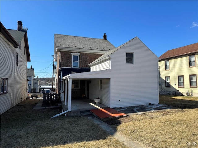 rear view of house featuring brick siding, a patio, and a yard