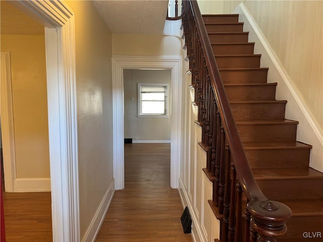 stairway featuring baseboards, visible vents, and wood finished floors