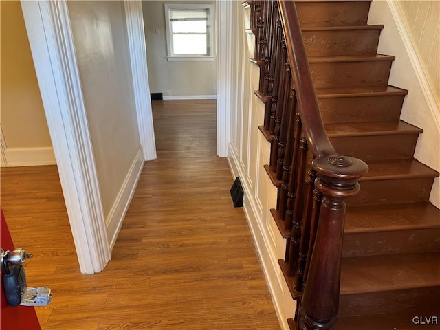 staircase featuring baseboards and wood finished floors