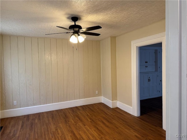 unfurnished room featuring a textured ceiling, dark wood-style flooring, a ceiling fan, and baseboards