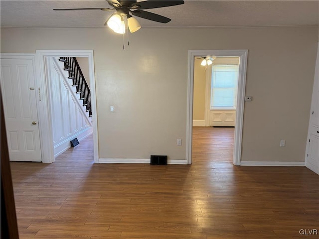 unfurnished room with baseboards, visible vents, stairway, and wood finished floors