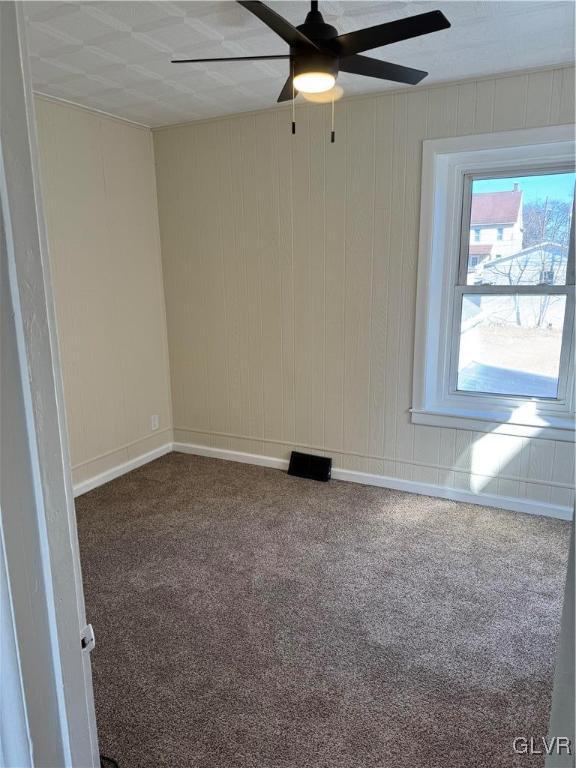 carpeted spare room with ceiling fan and baseboards