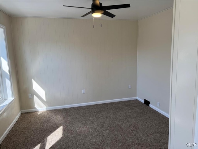 carpeted empty room featuring a healthy amount of sunlight, ceiling fan, and baseboards