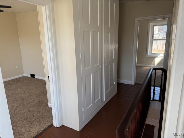 hallway with baseboards and dark carpet