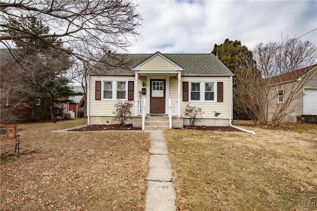 bungalow-style home featuring a shingled roof and a front lawn