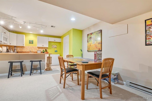 dining area featuring a baseboard heating unit, baseboards, and light colored carpet